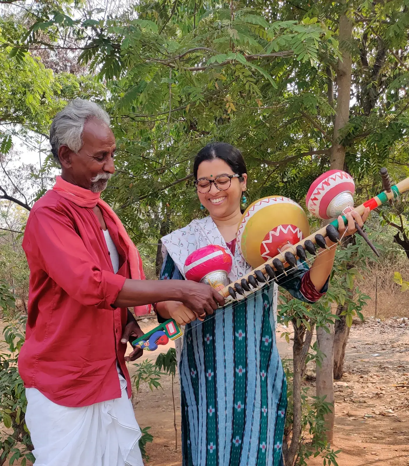 A Kinnera maker and the artist holding a Kinnera instrument outdoors